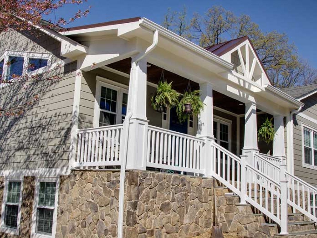 side view of a house with a white fence and hanging plants