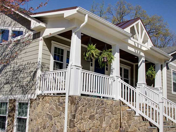 side view of a house with a white fence and hanging plants